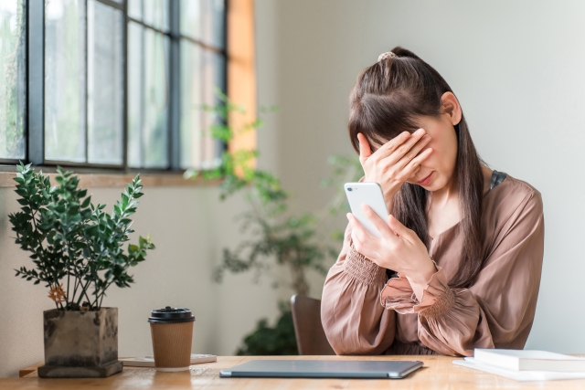 スマホを見て悩む女性